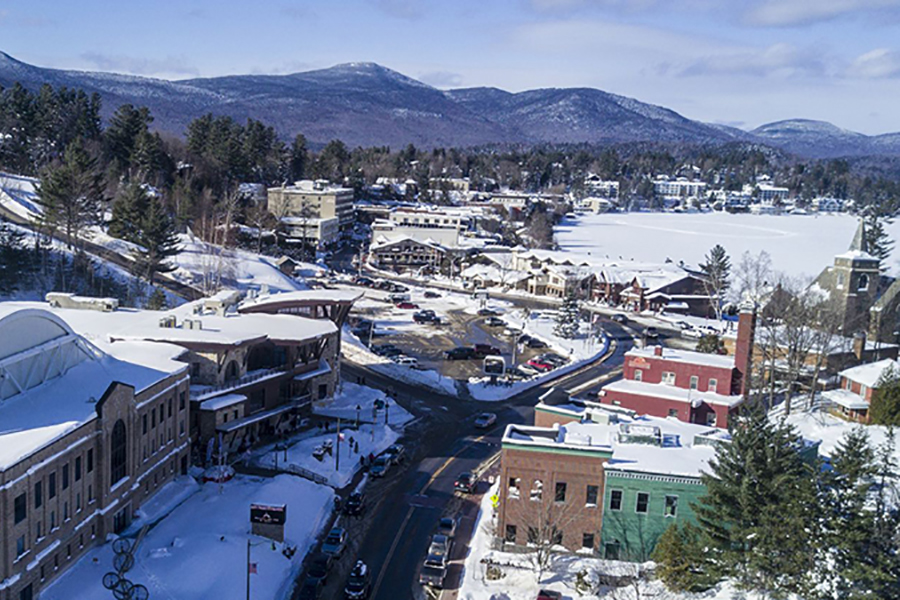 An aerial view of Lake Placid, New York, with show covered grounds and a variety of residential and commercial buildings