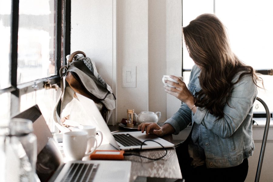 A woman sits at a desk with two laptop computers on it