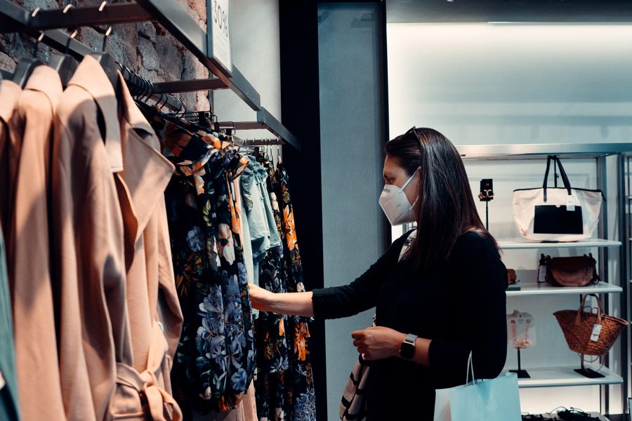 A woman wearing a face masks looks at clothing for sale in a department store