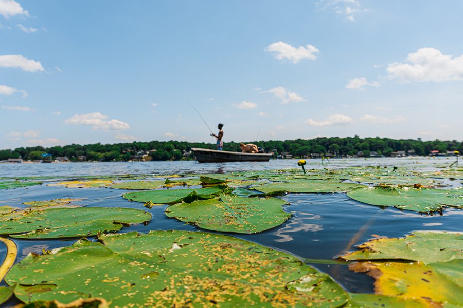 People fishing from a small boat in a lily pad-covered Lake Hopatcong in the New Jersey Highlands