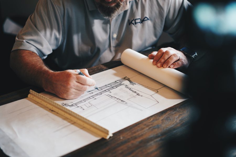 An architect completes a building rendering on paper. Photo by Daniel McCullough via Unsplash.