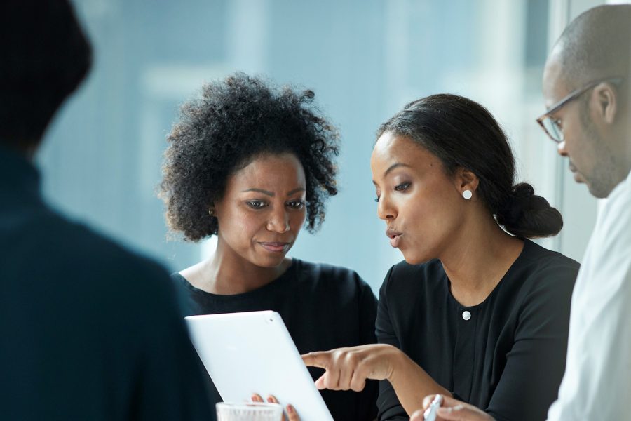 Four BIPOC people review a business plan on a laptop in a meeting