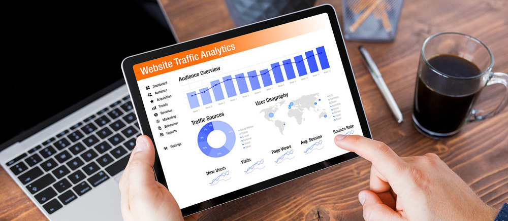 Close up of hands holding a tablet computer that is displaying website traffic analytics.