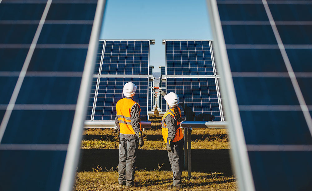 Two workers check an array of solar energy panels.