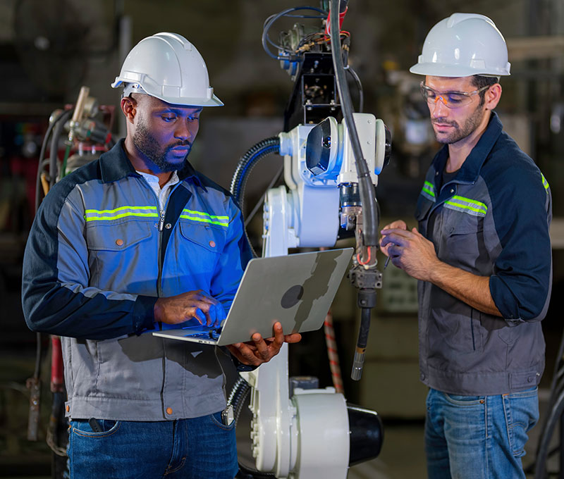 Two Advanced Manufacturing workers program a robotic arm