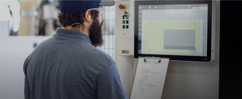 man looking at clipboard and a computer screen of data