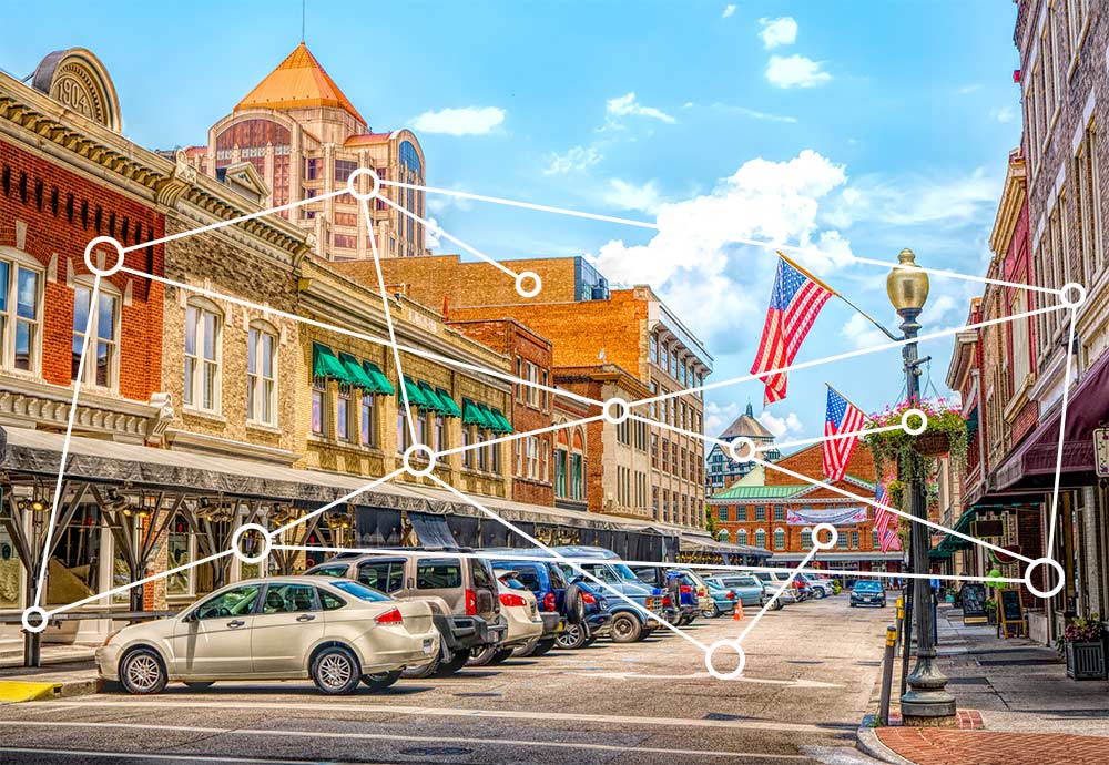 Photo of a downtown shopping area with network/connection lines between buildings and other objects illustrates an entrepreneurial ecosystem