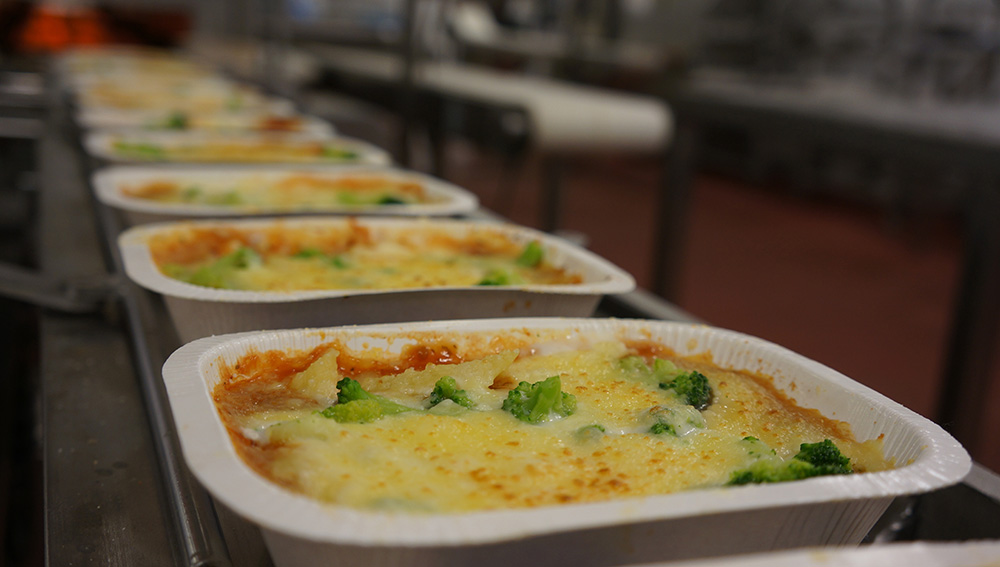 Trays of heat-and-eat dinners on a food production company conveyor belt