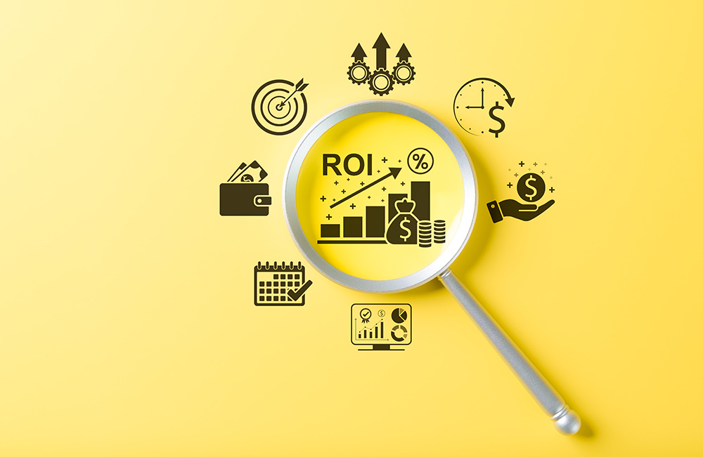 A silver magnifying glass examines return on investment (ROI), represented by an icon showing a column chart with increasing profits. Additional icons surround the magnifying glass, representing hitting targets, increased productivity, better time management, efficient use of time, data analysis, and money in your hand and wallet