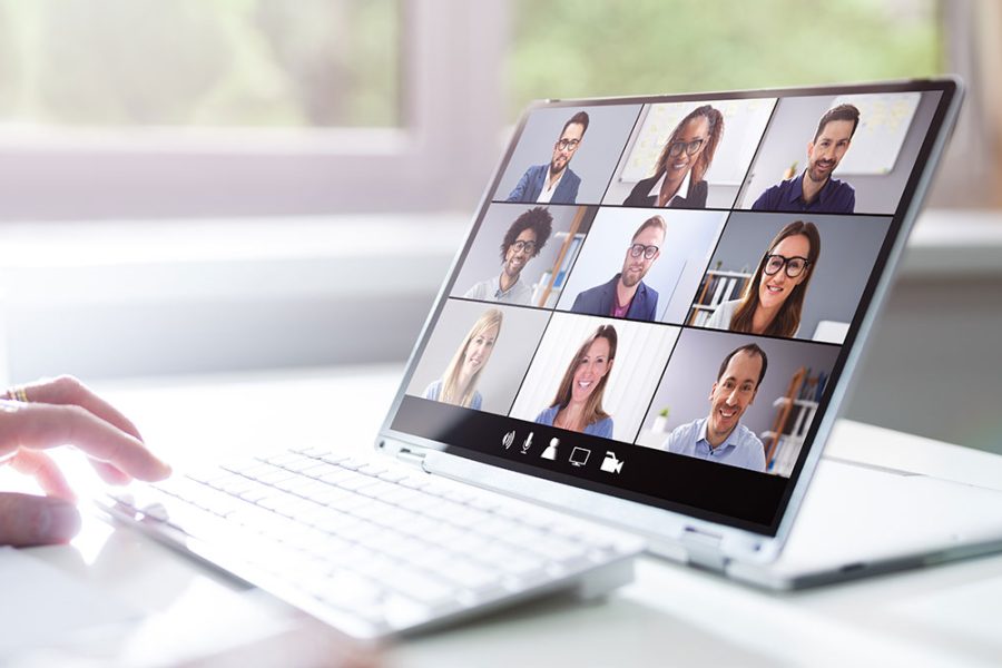 A person uses a laptop computer to provide virtual training for nine other people.