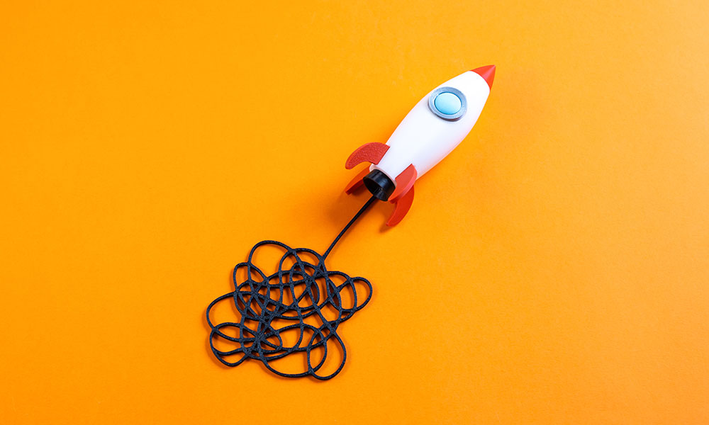 A rocket ship-shaped lamp with a long, very tangled chord illustrates challenges to innovation with AI.