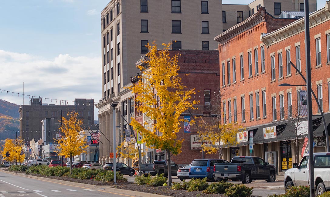 A downtown street in Olean, New York, is lined with small businesses in historical buildings with cars parked out front