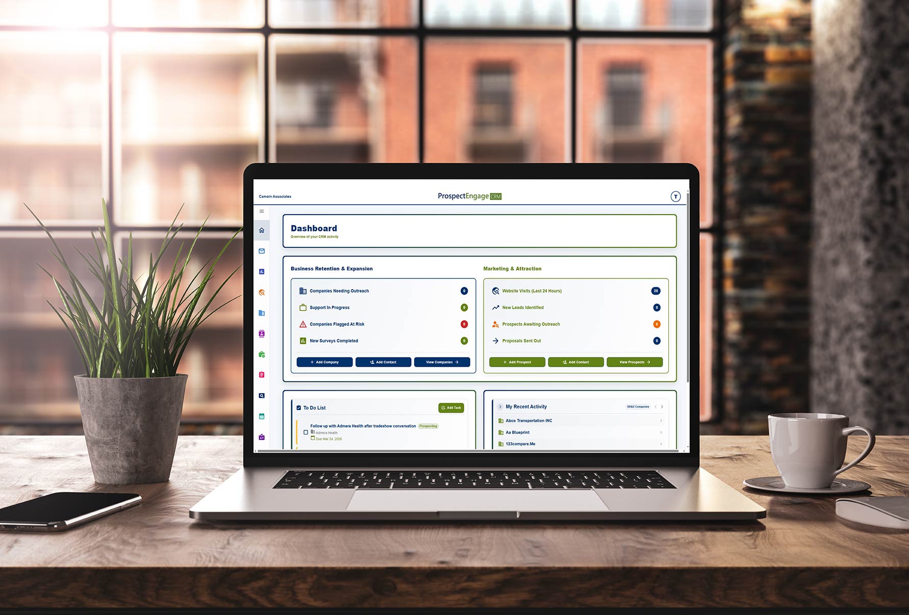 A laptop computer is open on a desk in an office building. The ProspectEngage CRM dashboard is visible on the laptop screen.