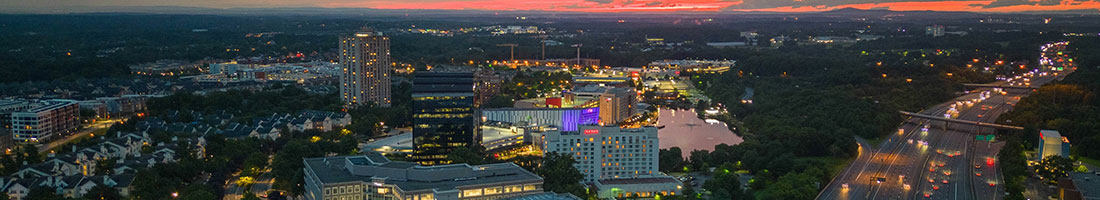 An aerial photo of Gaithersburg, Maryland, at sunset shows the city next to a busy multi-lane freeway